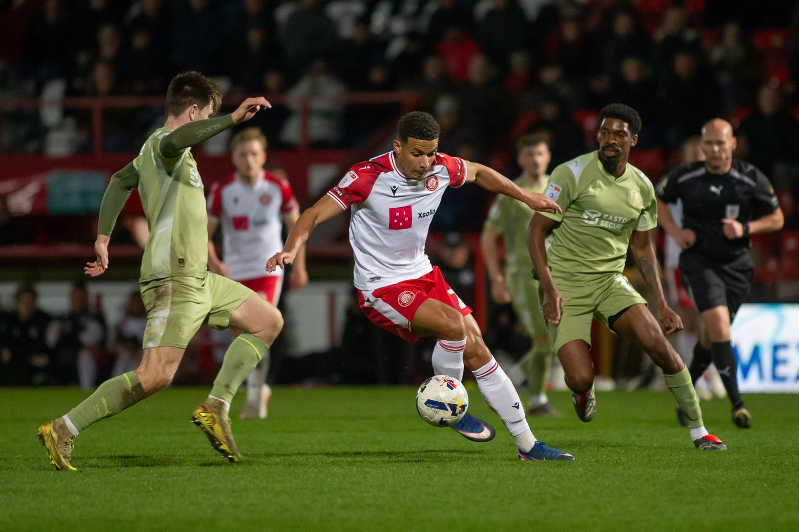 Luther James-Wildin heading the ball during a match, floodlights behind him